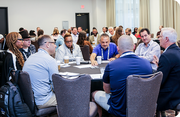 A diverse group of facility professionals seated at a workshop table during IFMA’s Facility Fusion, engaging in learning and discussion.